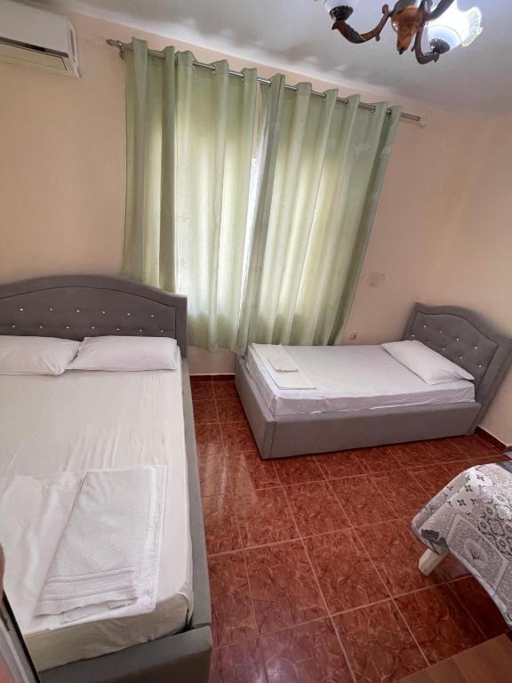 two beds in a room with a window at Hotel Gjika in Sarandë