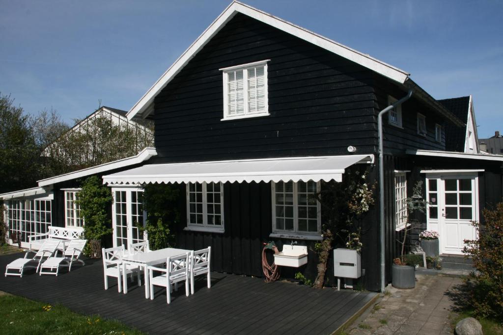 a black house with a deck with a table and chairs at Villa Humlebæk B&B in Humlebæk
