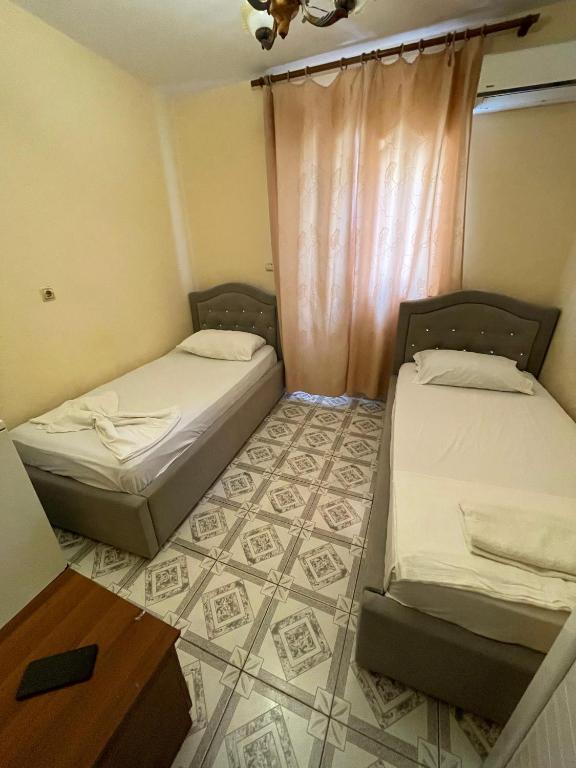 two beds in a small room with a table at Hotel Gjika in Sarandë