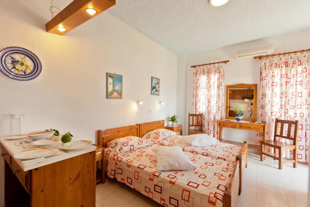 a bedroom with a bed and a table and a desk at Sofia's Garden Studios in Skopelos Town