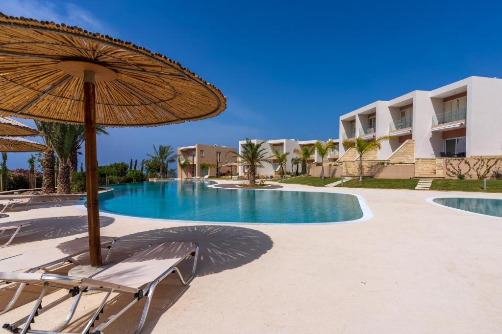 una piscina con sombrilla y sillas y un edificio en Elegant villa with pool view, en Klorakas
