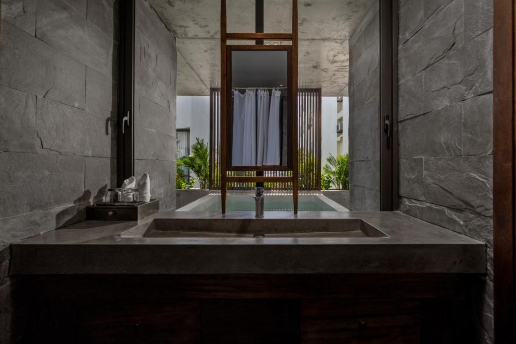 A dark-stone bathroom vanity faces a large mirror and a small central window.