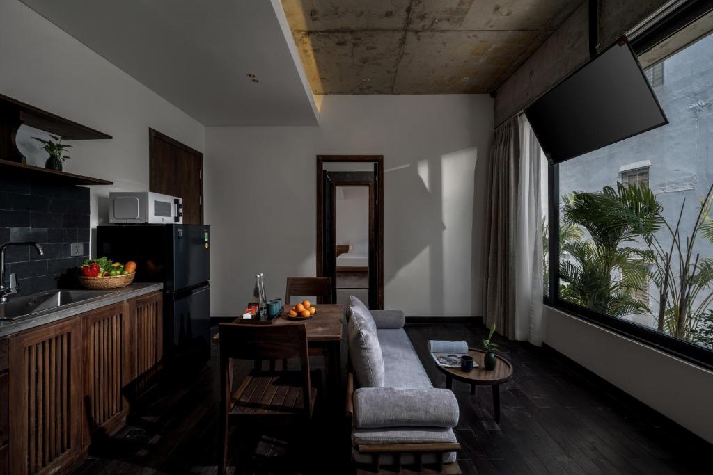 A living room with a kitchenette, dining table, sofa, and wall-mounted television.