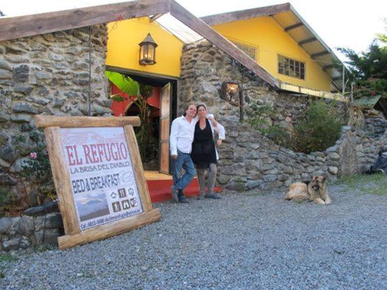 um homem e uma mulher em frente a uma casa em El Refugio La Brisa del Diablo em Valle Hornito