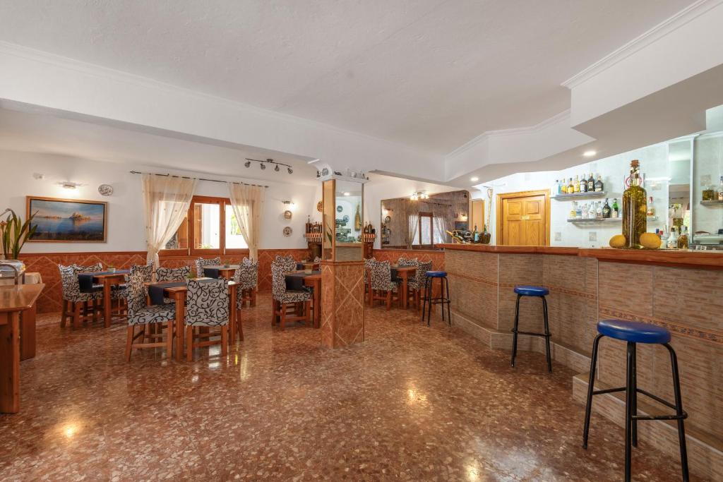 a restaurant with tables and chairs and a bar at Pensión las 3 Golondrinas in Santa Eularia des Riu