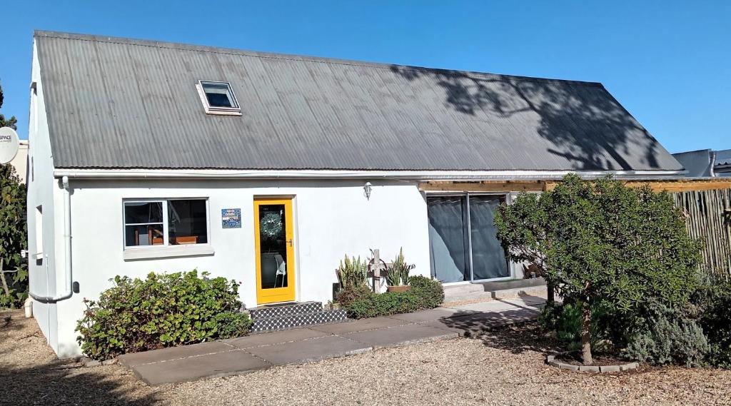 a white house with a yellow door at The Boathouse in Velddrif