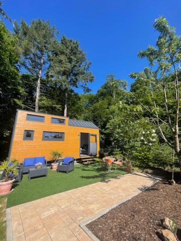ein kleines gelbes Haus mit blauen Stühlen in einem Garten in der Unterkunft Tiny-Haus in Boppard