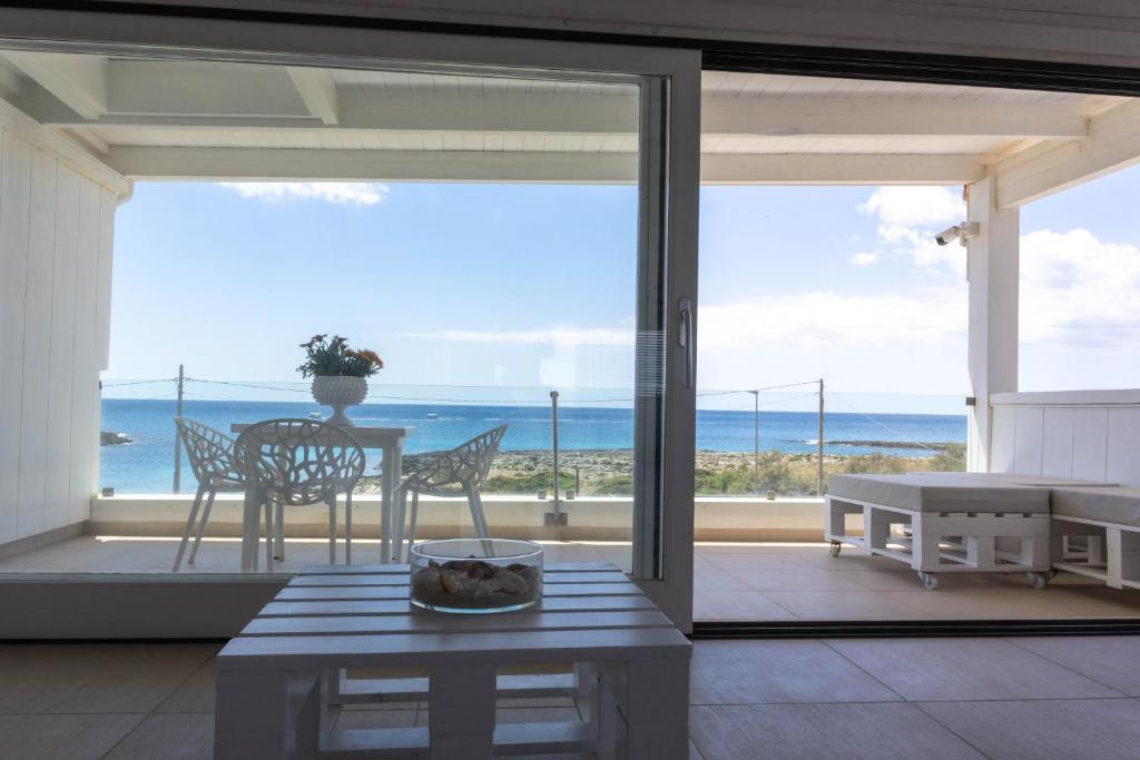 a living room with a table and a view of the ocean at Casa Dansodà sul mare in Torre Lapillo