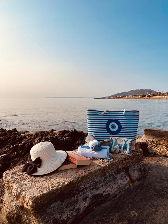 a hat and other items sitting on a ledge near the water at Airport Cottage House in Artemida