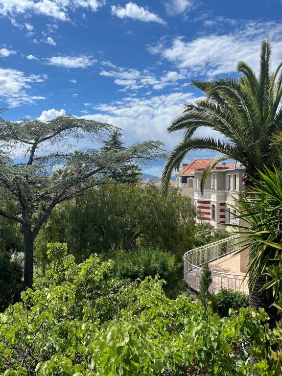 - une vue sur un bâtiment avec des arbres et des buissons dans l'établissement Villa belle époque idéalement située plage et centre ville, à Saint-Raphaël