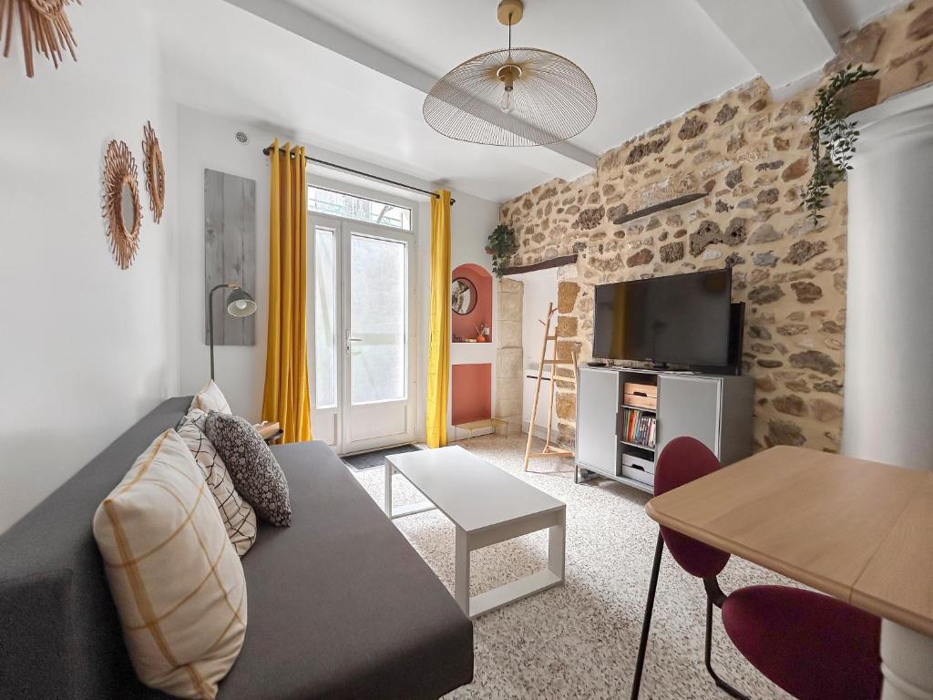 un salon avec un canapé et un mur en pierre dans l'établissement Appartement Cosy au calme, à Noves
