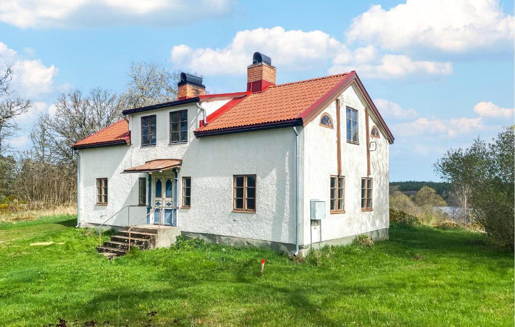 an old white house with a red roof on a field at 1 Bedroom Amazing Home In Mörlunda in Mörlunda