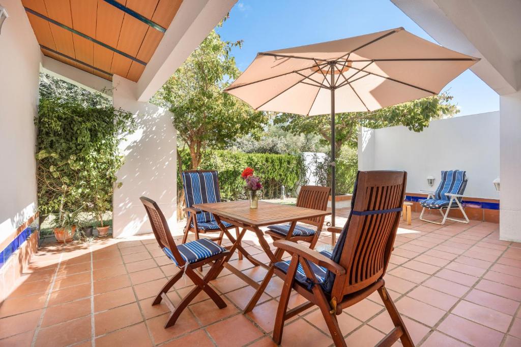 a patio with a table and chairs and an umbrella at Villa Camaleón in Chiclana de la Frontera