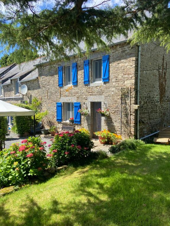 a stone house with blue windows and flowers at Pinabre Farmhouse in Plouguenast Langast