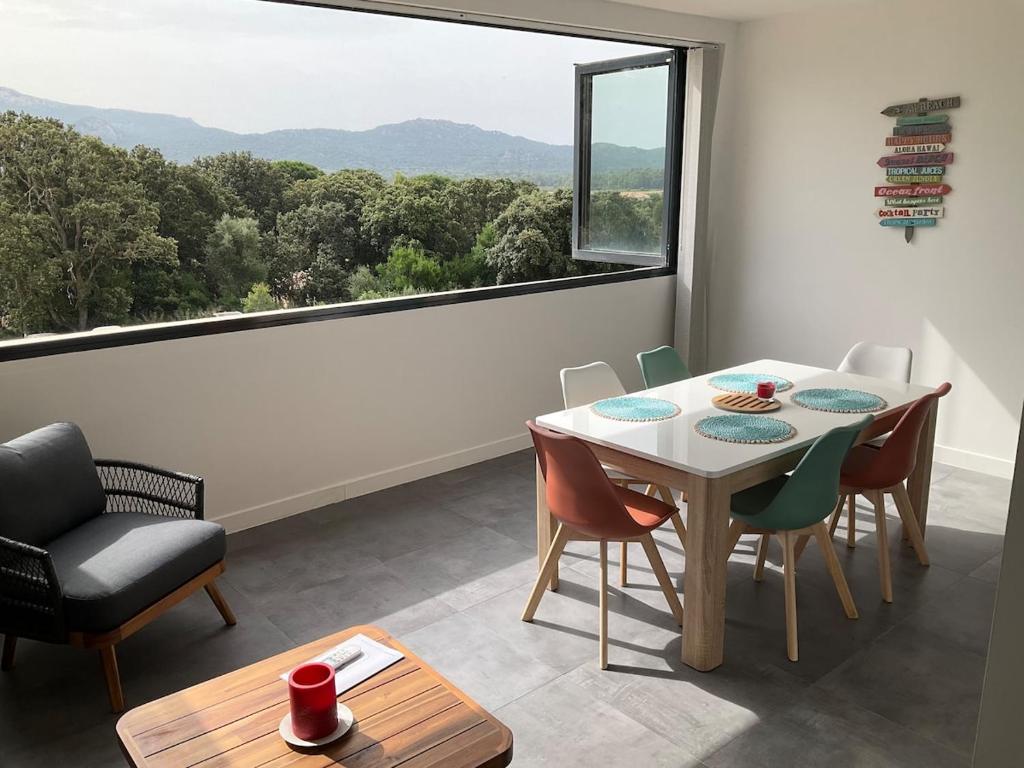 une salle à manger avec une table et des chaises et une grande fenêtre dans l'établissement Apartment in Porto-Vecchio with pool, à Porto-Vecchio