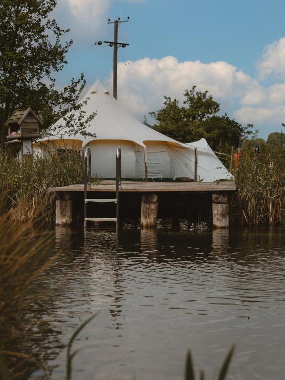 a boat on a dock in a body of water at Moat Island Glamping in Norwich