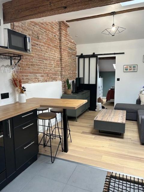 une cuisine et un salon avec une table et un canapé dans l'établissement T2 de charme, au cœur de ville avec climatisation, à Toulouse