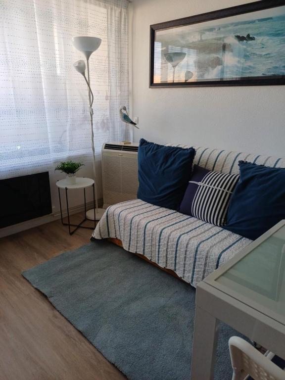 un salon avec un canapé avec des coussins bleus dans l'établissement Le nid des hirondelles, à Leucate-Plage