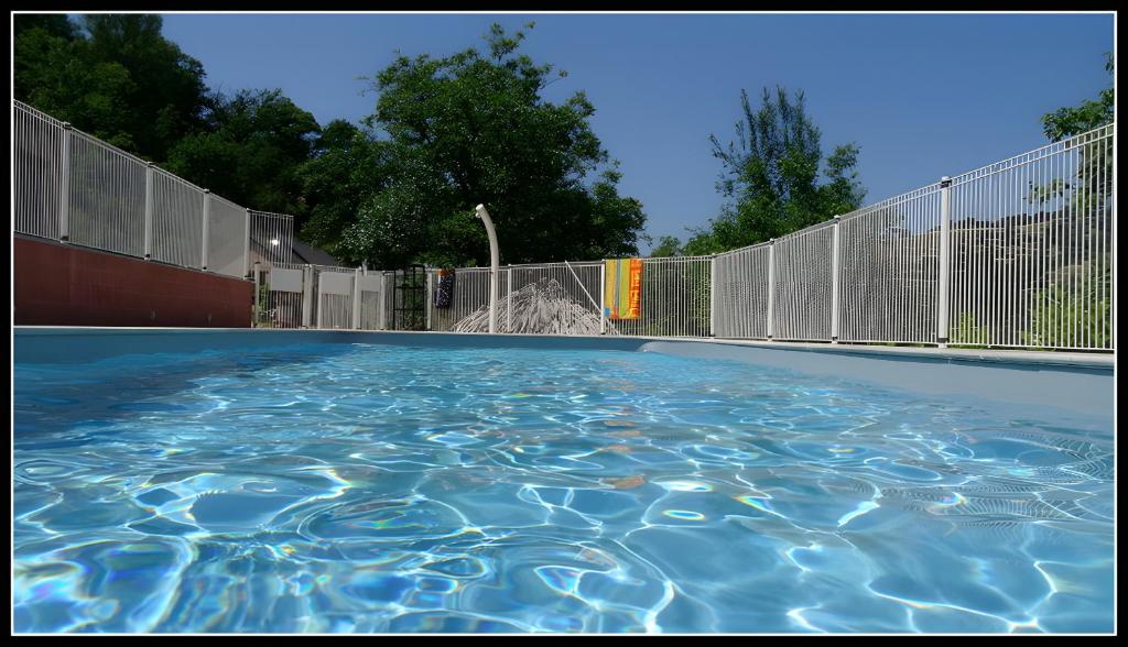une piscine avec une clôture et une fontaine dans l'établissement Domaine de Jouani gîte La Charrue, à Villecomtal