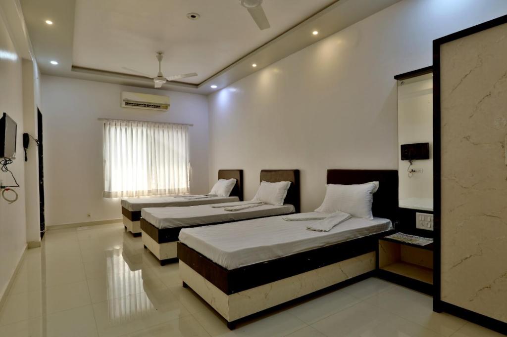 NavsāriHotel Sai Navsari的有窗户的房间里有两张床