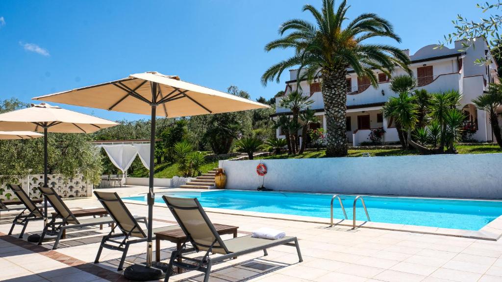 a pool with chairs and umbrellas next to a house at Villa Poggio di Luna con piscina privata in Peschici