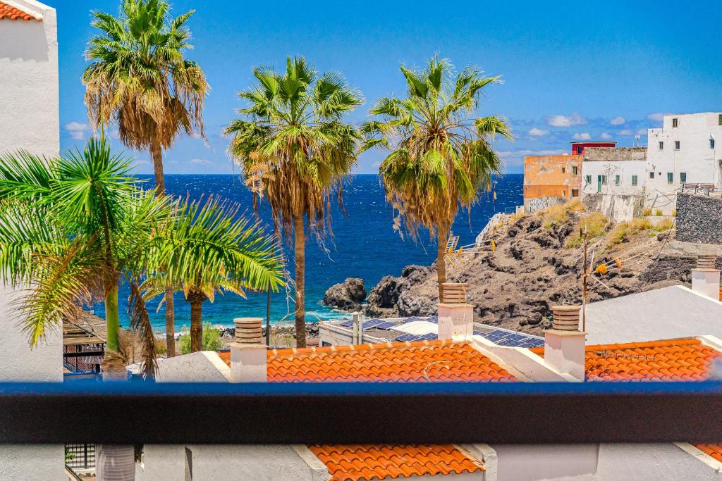 Blick auf einen Strand mit Palmen und das Meer in der Unterkunft Family flat with 3 bedrooms and balcony near Los Gigantes and ocean in Puerto de Santiago