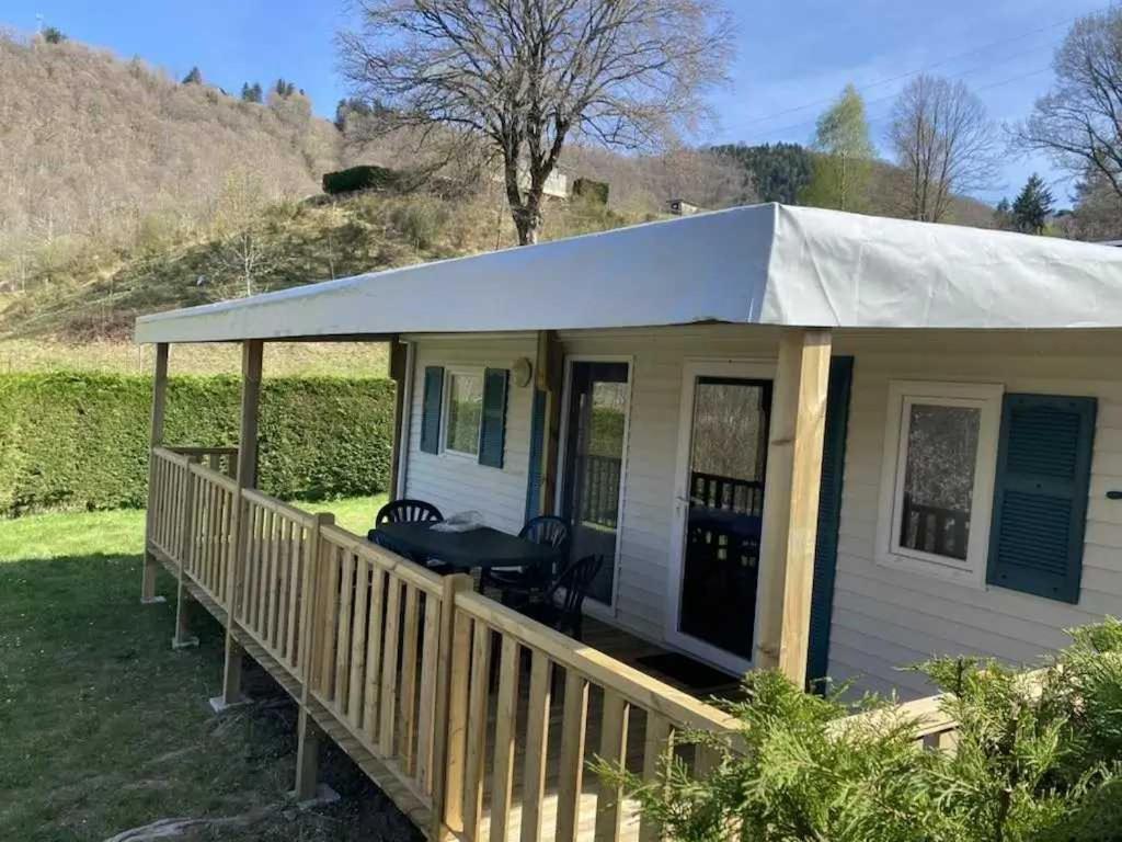a small white house with a tent on a porch at Camping - Piscine - ccbbdag in Vic-sur-Cère