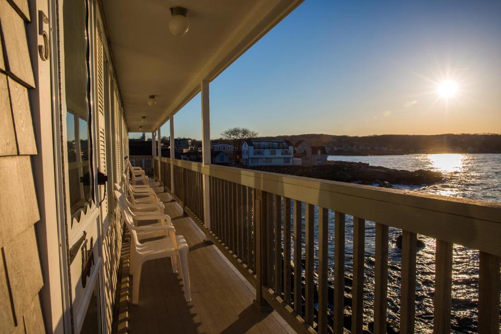 a row of chairs on a balcony overlooking the water at Bearskin Neck Motor Lodge in Rockport