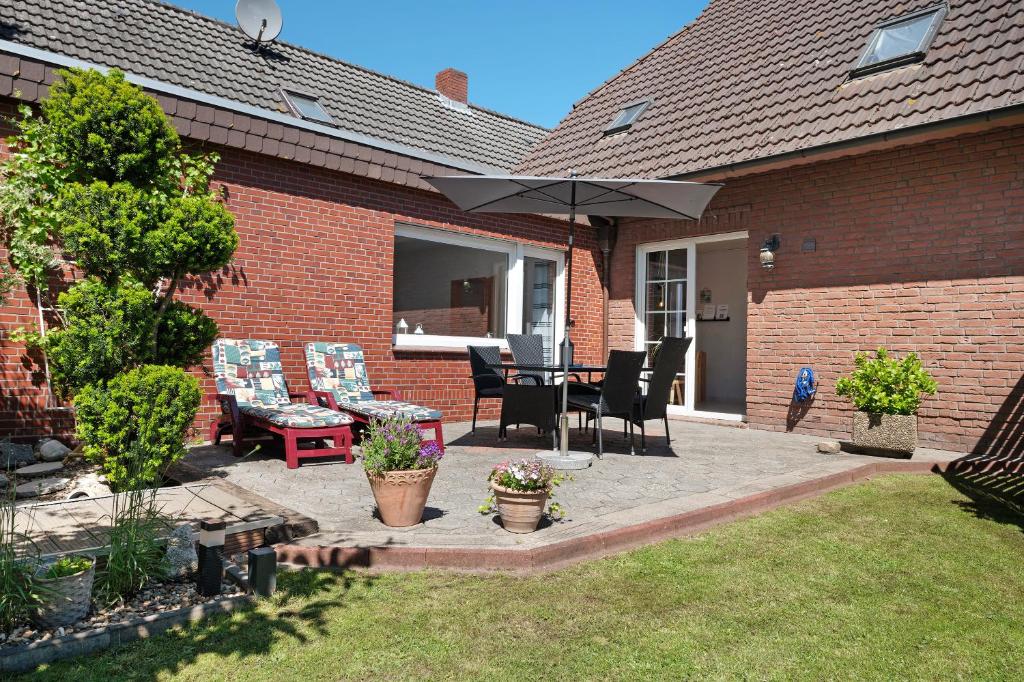 a patio with a table and chairs and an umbrella at Ferienwohnung Wilma Spetzerfehn in Großefehn 
