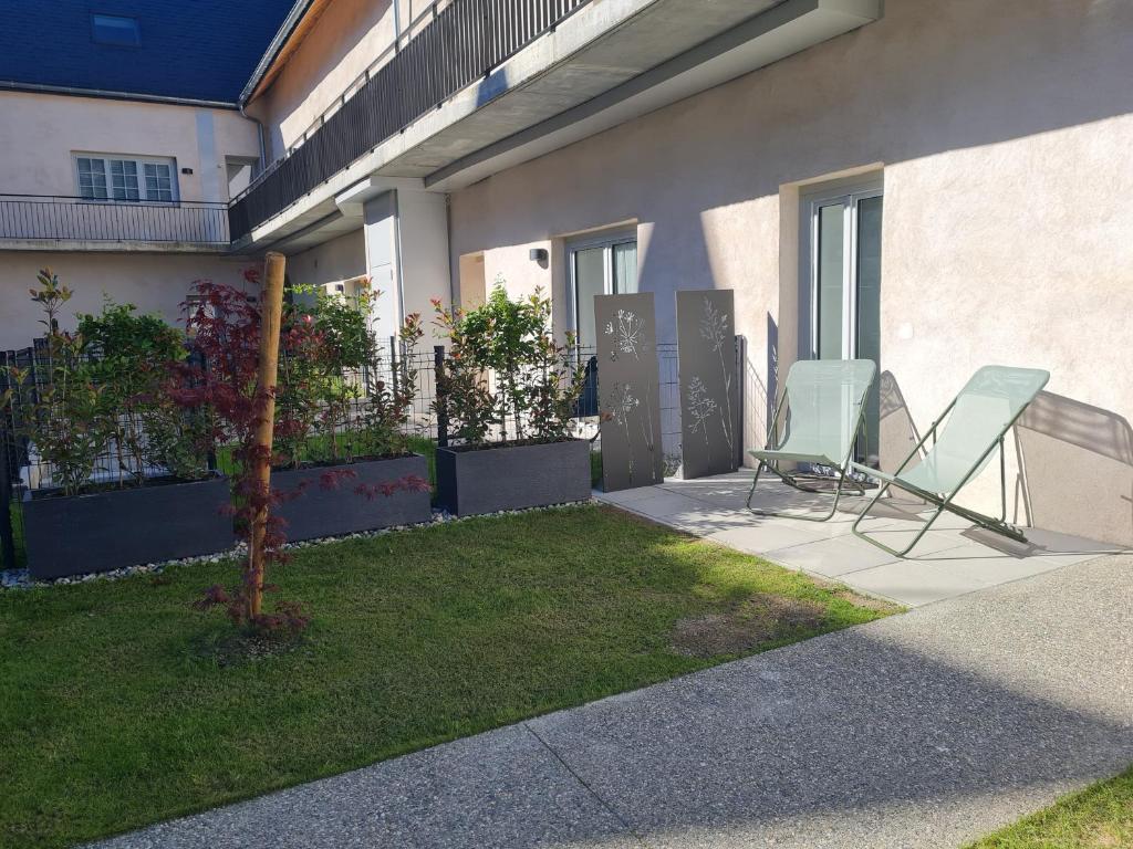 2 chaises assises dans la cour d'une maison dans l'établissement Apartement Les Ondes, à Albertville