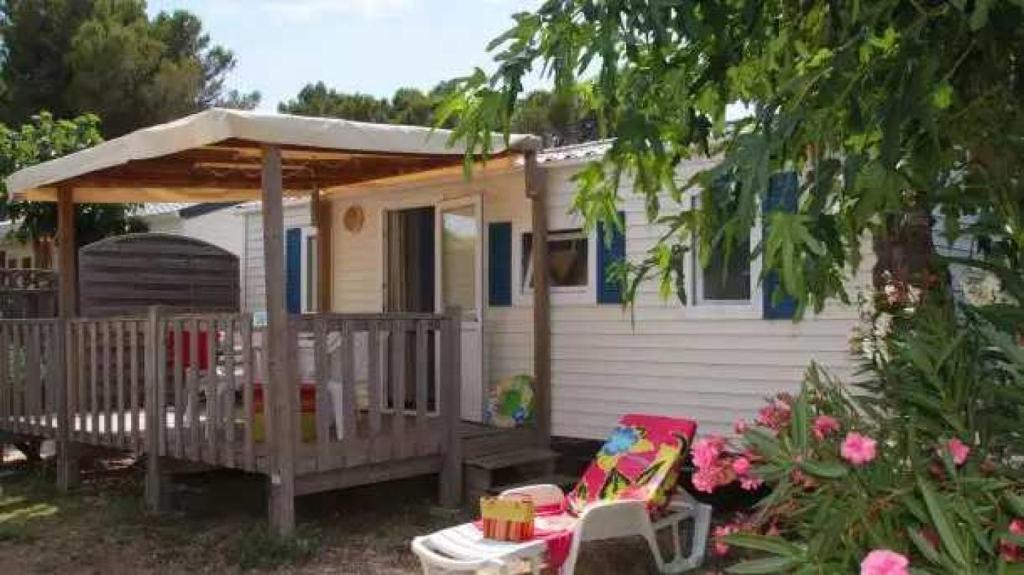 une petite maison avec une terrasse couverte et 2 chaises dans l'établissement Appartement 4 étoiles - Parc aquatique - ccaa0ai, à Bormes-les-Mimosas