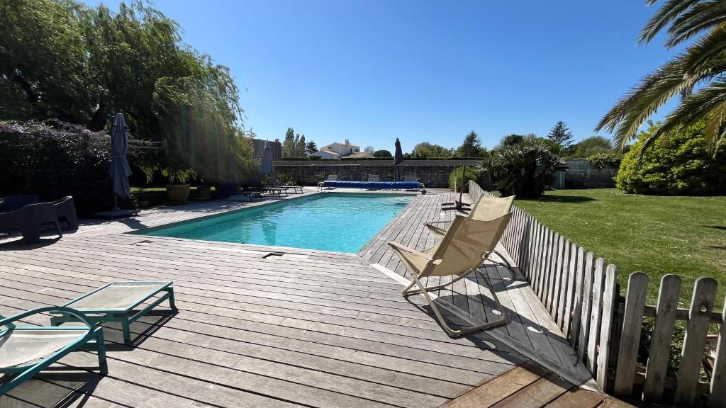 a deck with a swimming pool and two lawn chairs at Maison atypique familiale in Étaules
