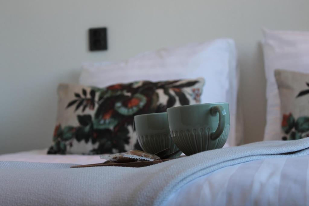 a coffee cup sitting on top of a bed at Estrela Do Norte in De Cocksdorp