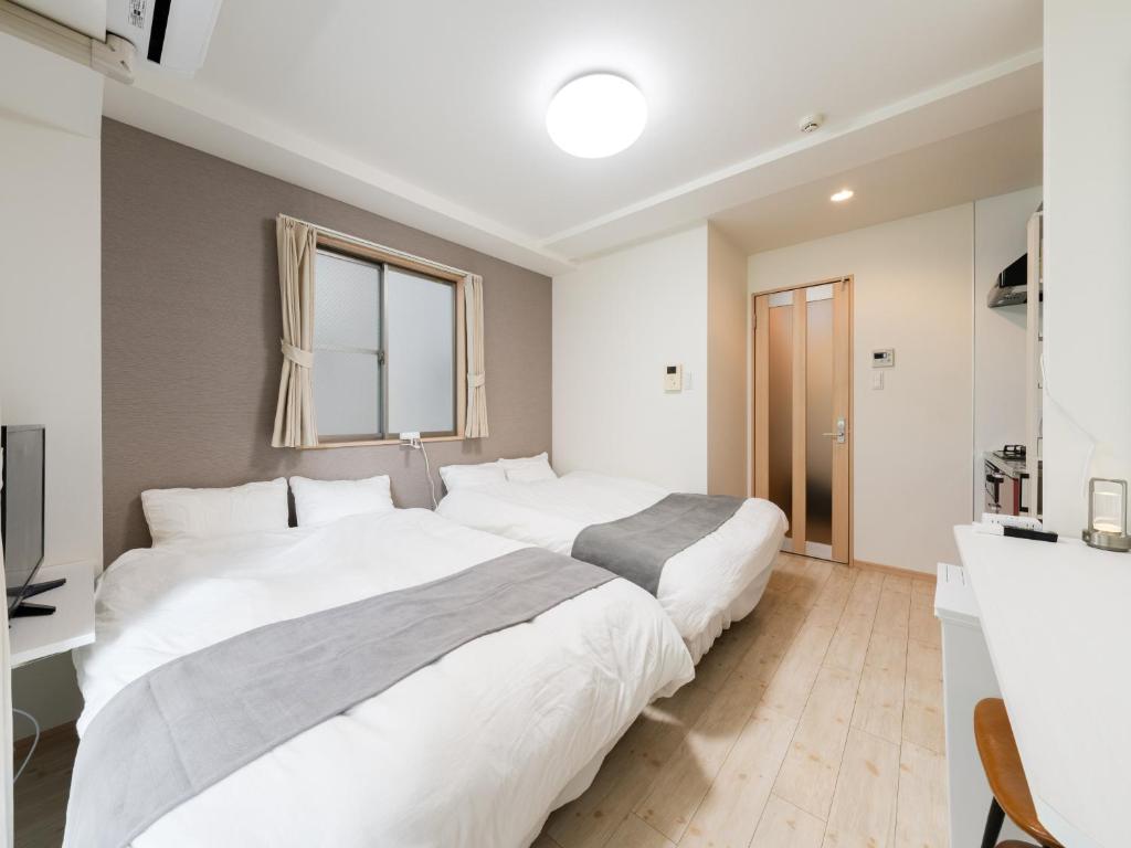 two beds in a white bedroom with a window at Ikebukuro 10 min-Family-Friendly Stay-Mobile Wi-Fi&Switch-Net in Tokyo