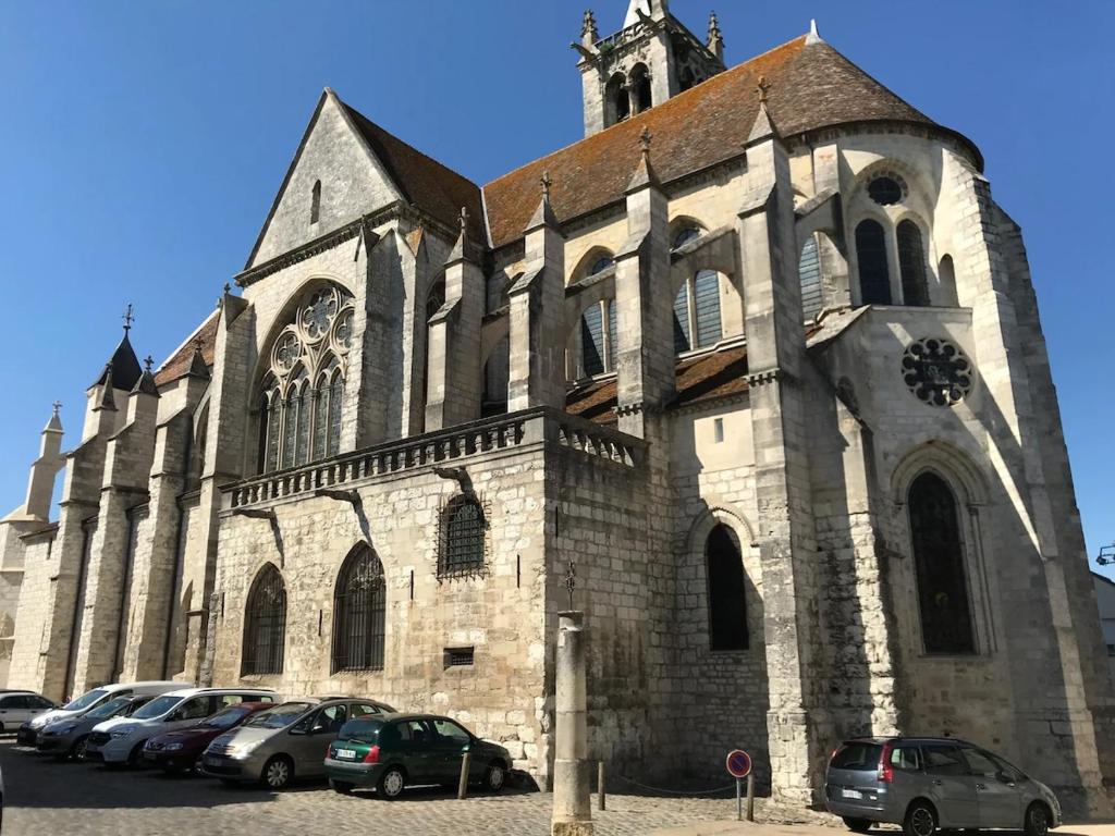 une église avec des voitures garées devant dans l'établissement L'escapade Royale, à Moret-sur-Loing