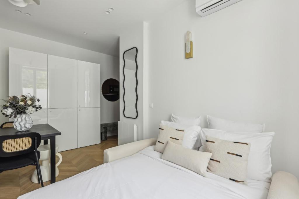 Dormitorio blanco con cama blanca y mesa en Appartement Guersant Pereire, en París