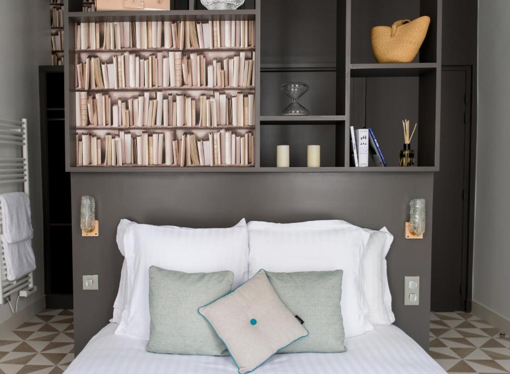 uma cama com almofadas brancas e uma prateleira com livros em 1er Etage Opéra em Paris