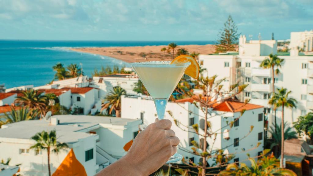 a person holding a martini in front of a city at Labranda Marieta & Spa - Adults Only in Playa del Ingles