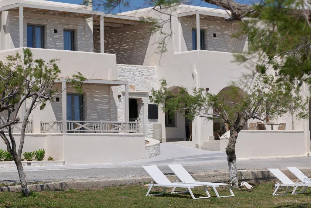 una fila de sillas blancas delante de una casa en Salt Suites Paros, en Naousa