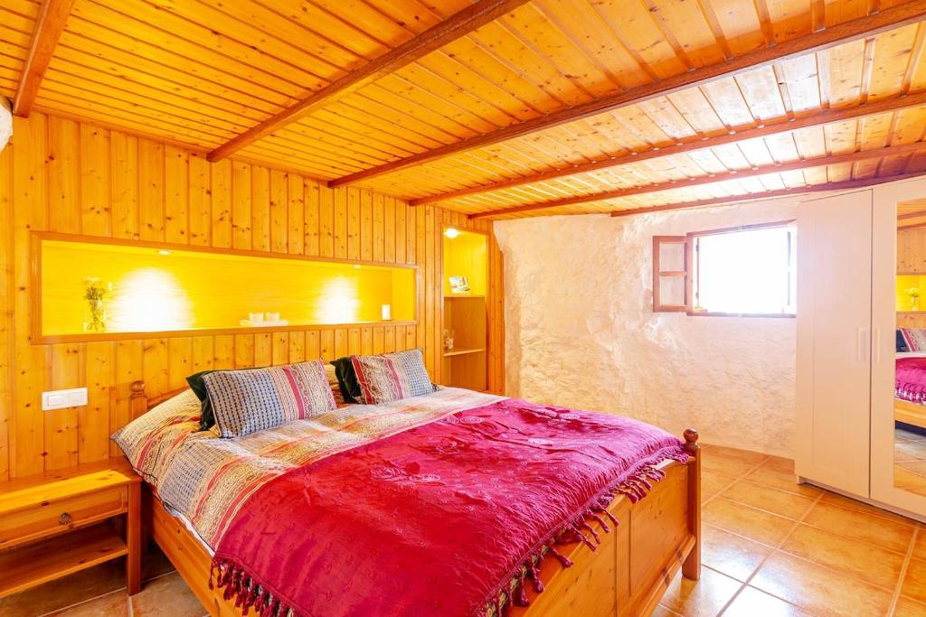 ein Schlafzimmer mit einem Bett in einem Holzzimmer in der Unterkunft La Cueva de Tito-Casa Cueva en plena naturaleza in Santa Brígida
