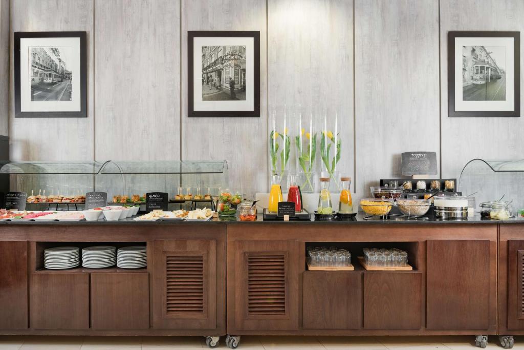 A buffet counter presents pastries, fruit, juices and chilled breakfast items beneath glass covers.
