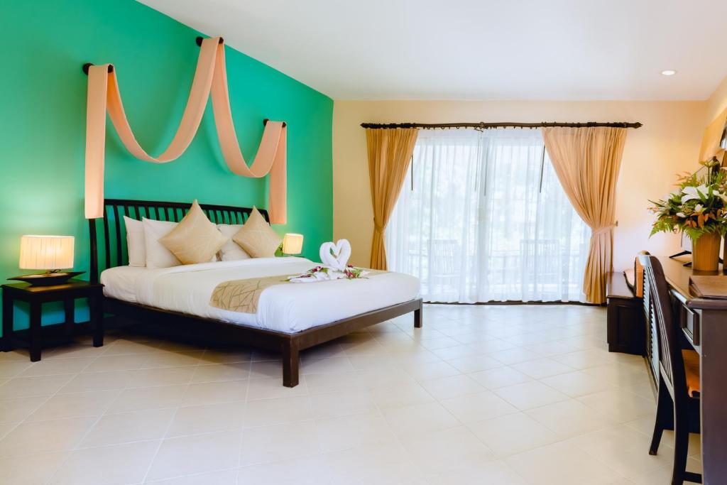 a bedroom with a bed and a green wall at Sudala Beach Resort in Khao Lak