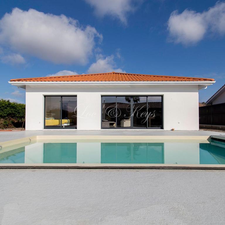 une maison avec une piscine devant dans l'établissement Bisca jolie maison-piscine, à Biscarrosse