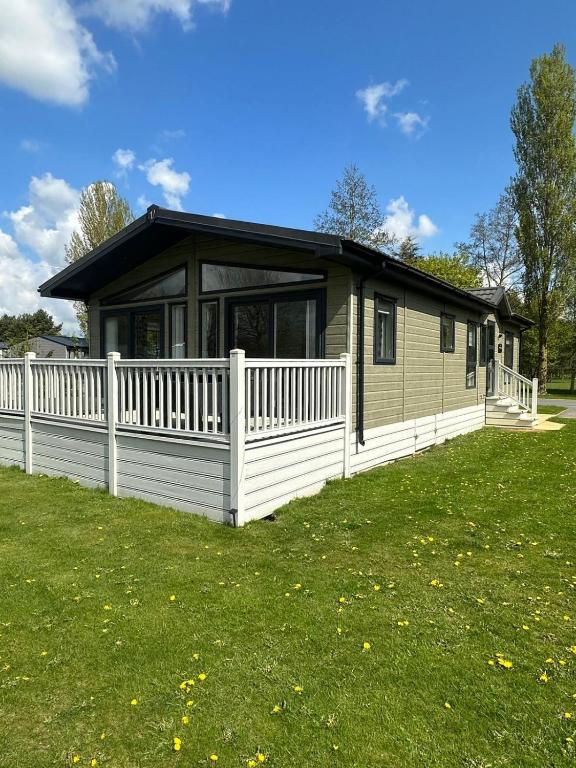 une petite maison avec une clôture blanche dans une cour dans l'établissement Oakmont 4 - Lodge with Hot Tub, à Allerthorpe