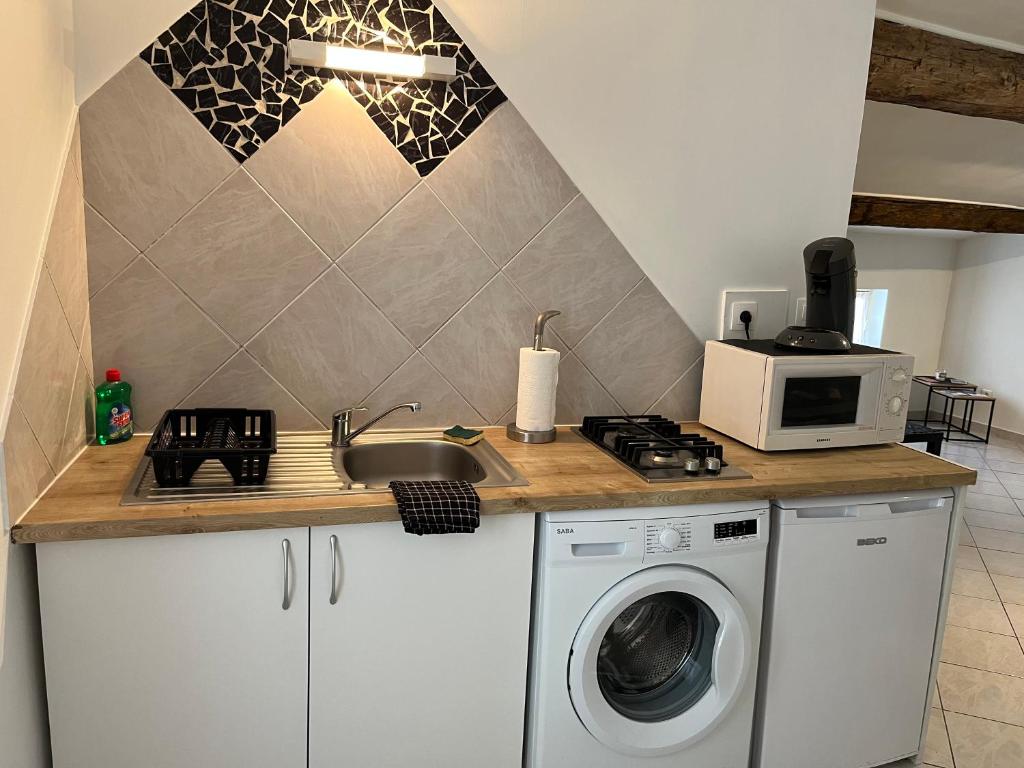 une cuisine avec un lave-linge et un micro-ondes dans l'établissement Épices 1 au cœur du centre ville historique de Serignan, à Sérignan