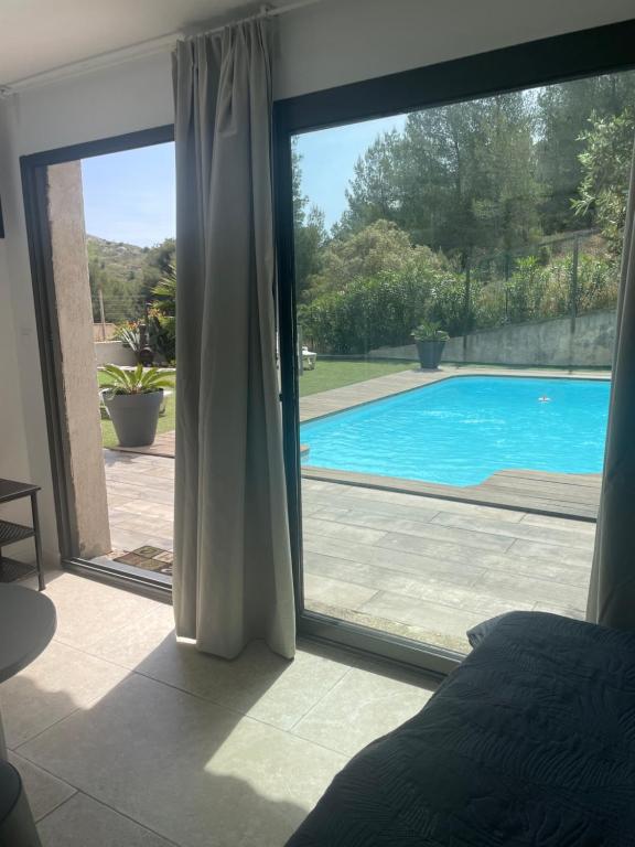 een slaapkamer met uitzicht op een zwembad via een glazen schuifdeur bij En Plein cœur des calanques à 800 m de la mer in Le Rove