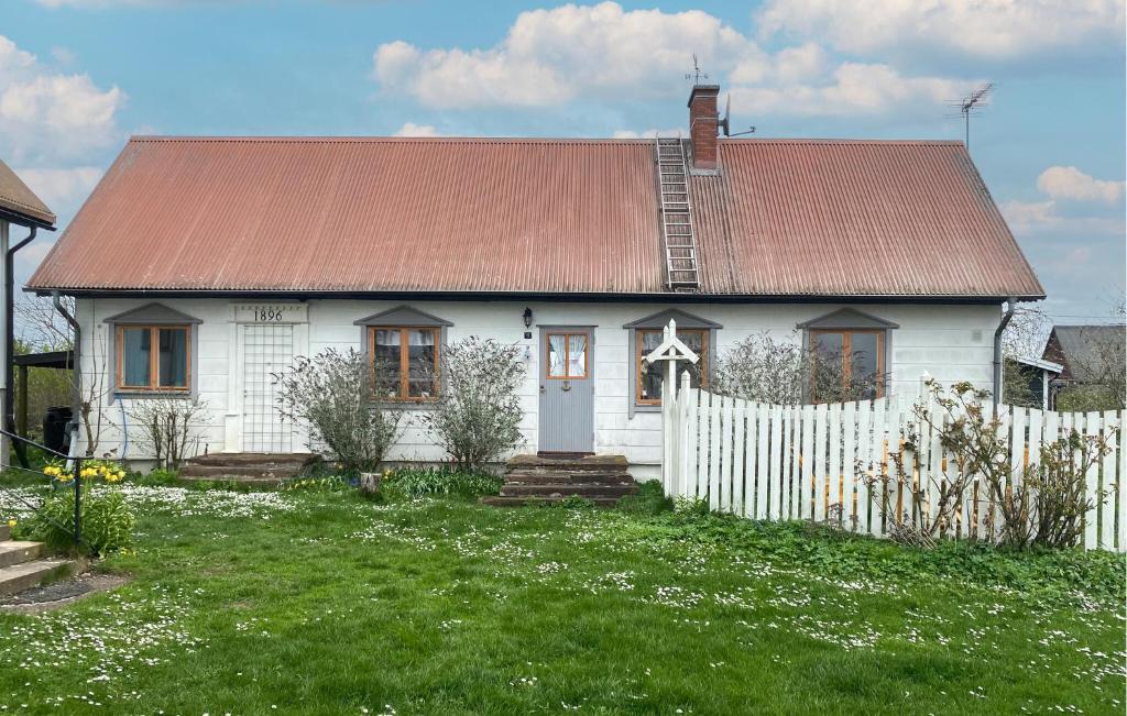 a white house with a red roof and a fence at 2 Bedroom Cozy Home In Melösa På Öland in Ekby