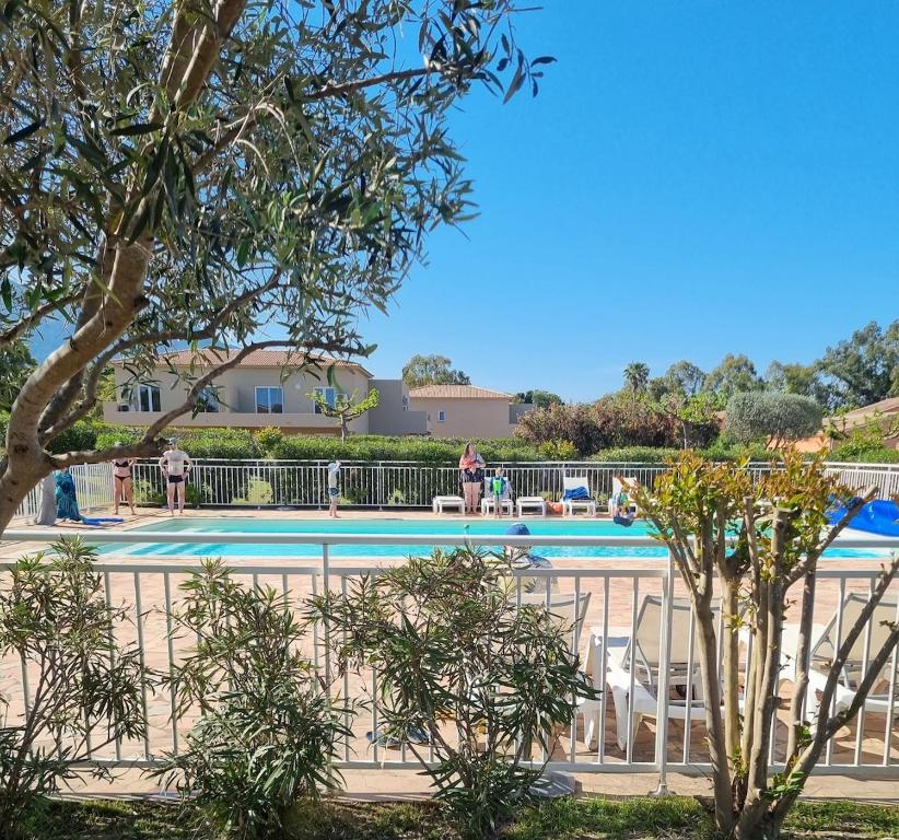 einen Pool in einem Resort mit Tischen und Stühlen in der Unterkunft Mini Villa 200 m de la plage in Cervione