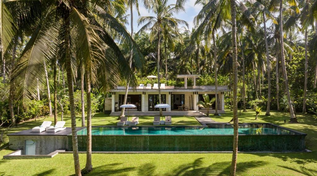 a villa with a swimming pool and palm trees at Kelapa Retreat & Spa in Pulukan