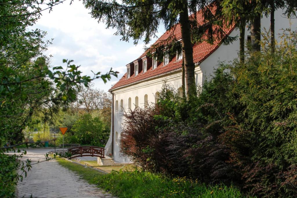 een wit gebouw met een rood dak en een bank bij Spichlerz Bliźniaczy in Kazimierz Dolny